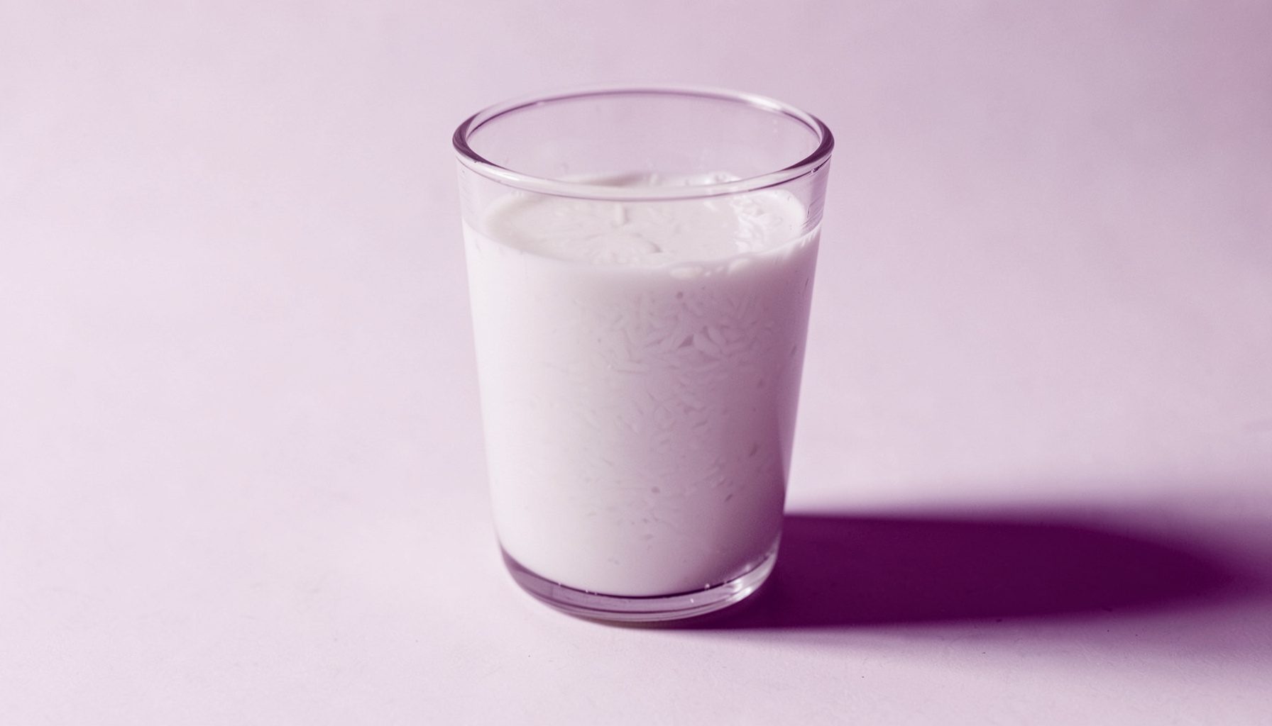 Recipiente de vidrio con agua de arroz de tono blanquecino lechoso sobre una superficie clara, iluminación natural suave.