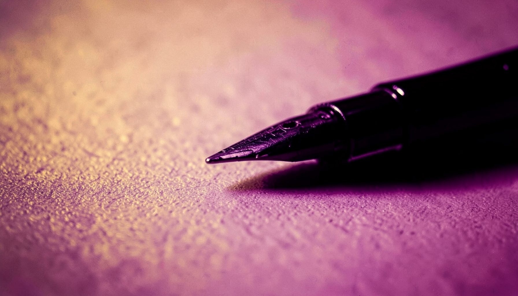 Primer plano de una pluma estilográfica sobre papel texturizado en tonos cálidos dorados y violetas profundos, atmósfera reflexiva.